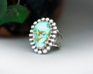 3/4 view facing left, pear shaped sonoran gold turquoise statement ring, the stone is light turquoise with darker turquoise and gold veining